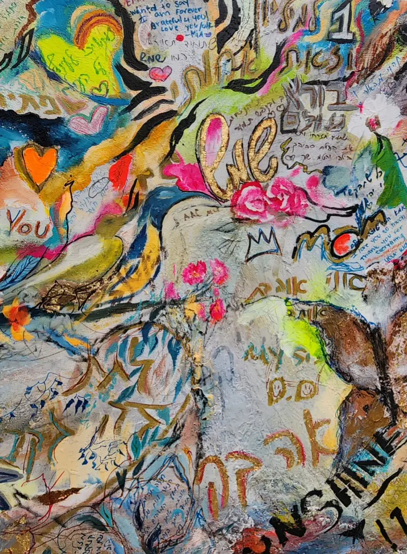 A birthday canvas covered in hearts, flowers and handwritten wishes in English and Hebrew